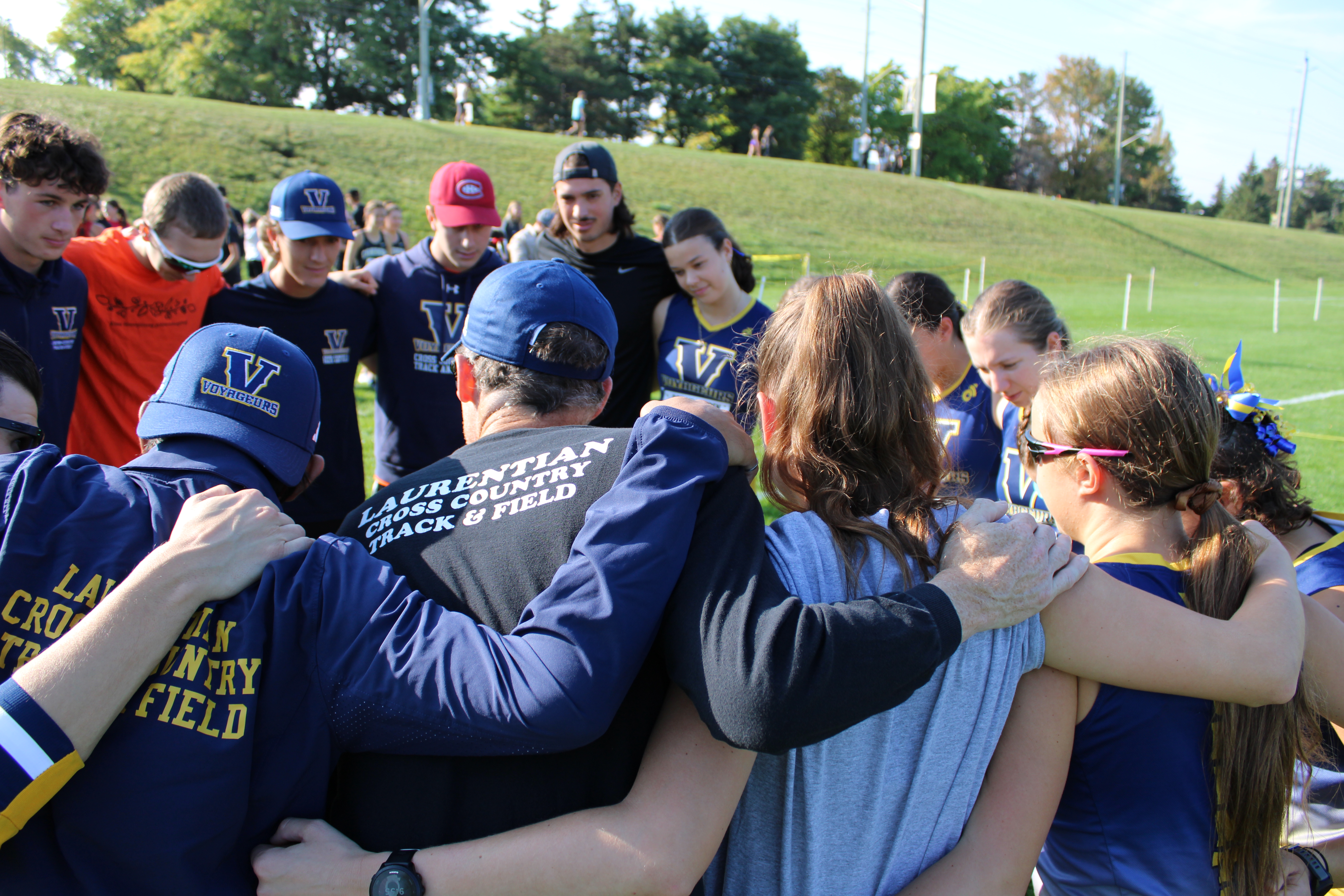 Members of the Laurentian Voyageurs cross-country team huddle together with arms around each other during a pre-race pep talk.
