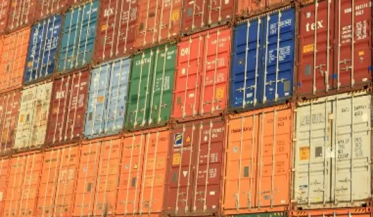 A lot of shipping containers stacked side by side and one on top of each other.