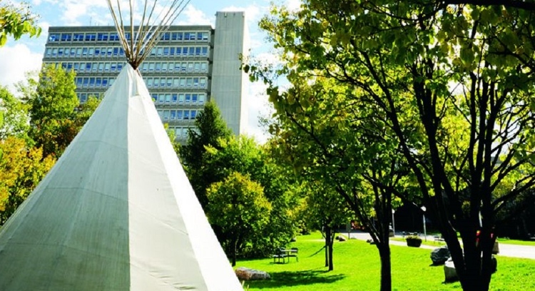 Une tente sur l'herbe devant un bâtiment universitaire