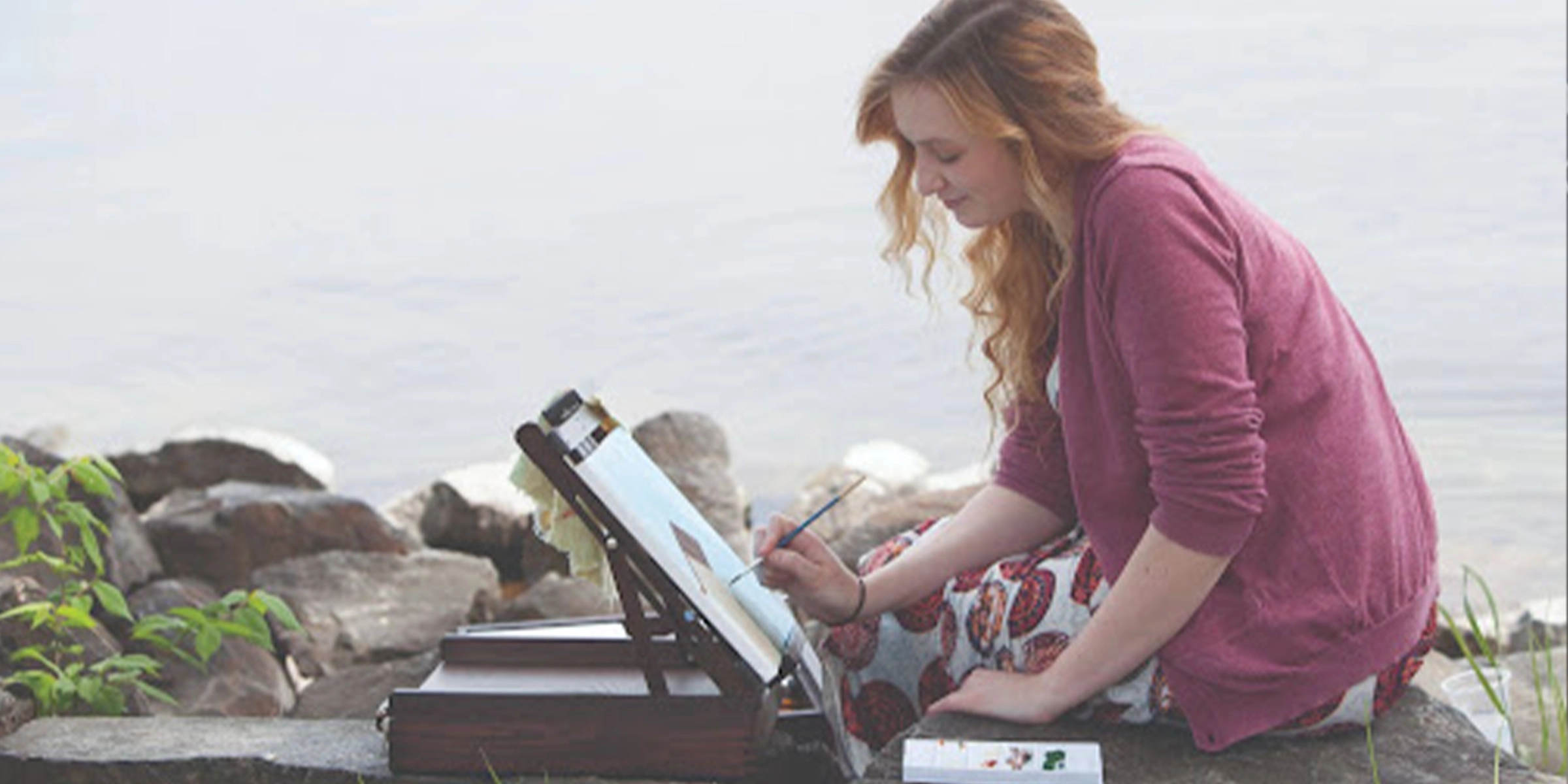 Student painting near a lake