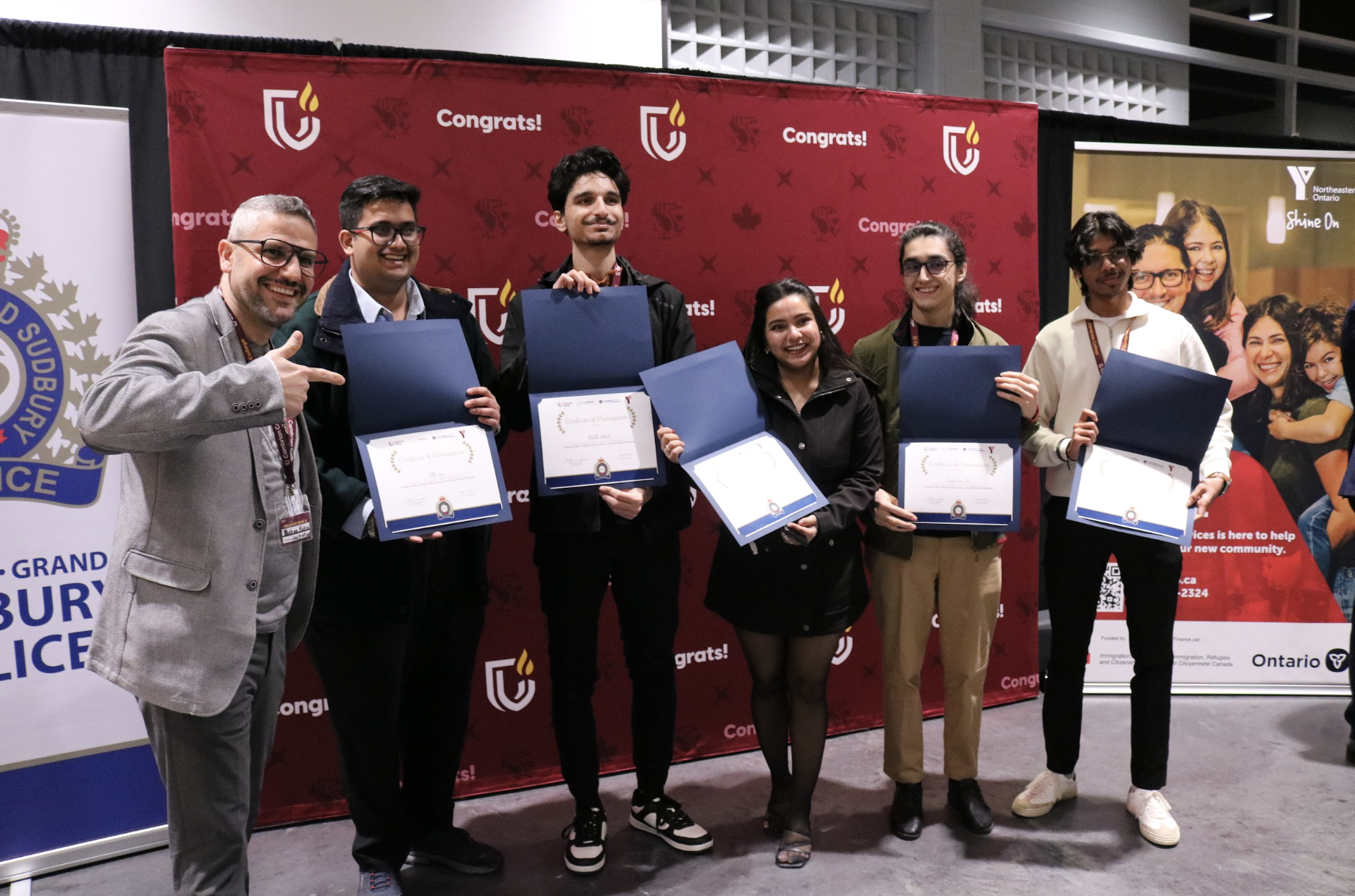 Bahaa Habra and five international students smiling while holding their program completion certificates.